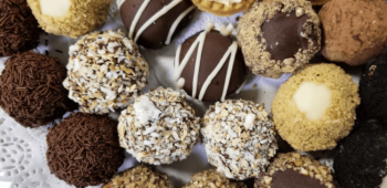 Assorted chocolate truffles and candies arranged closely together on a white paper doily.