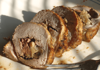 Three slices of stuffed roasted meat filled with chopped onions and mushrooms on a white plate with a fork.