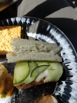 A plate with finger sandwiches: one with cucumber and cream, another with a creamy filling between white bread slices.