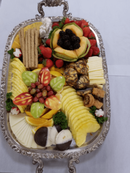 A silver tray with assorted fruit, cheese, pastries, cookies, and chocolate-covered treats arranged neatly.