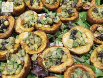 Potato cups filled with black bean, corn, and avocado salsa, served on a bed of mixed greens.